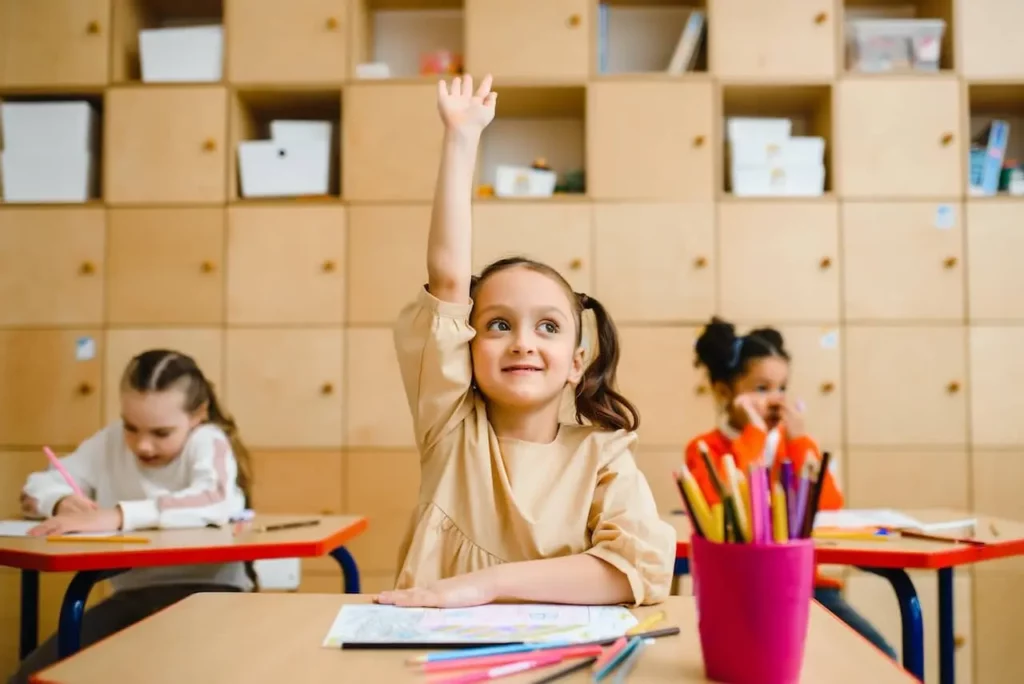 child raising hand in classroom