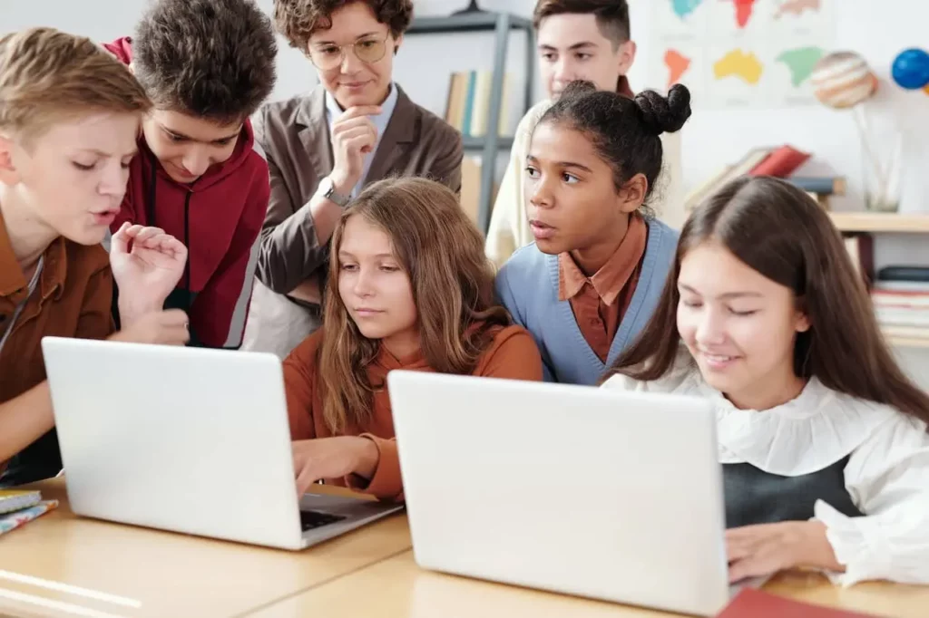 class of students looks at 2 computers